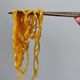 Pumpkin Spice Nissin Cup Noodles hanging from chopsticks